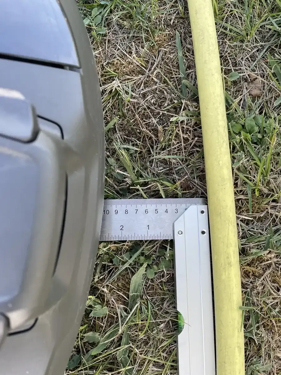 Règle entre la carrosserie du Husqvarna R6V et un tuyau d’arrosage jaune